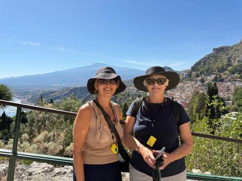 Two women posing with a scenic mountain view.