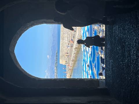 View through an arch of waterfront and people walking.