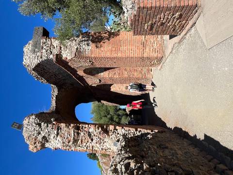 Tourists exploring a historic brick archway.