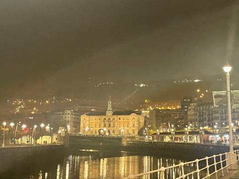 Cityscape at night with lights reflecting in water.