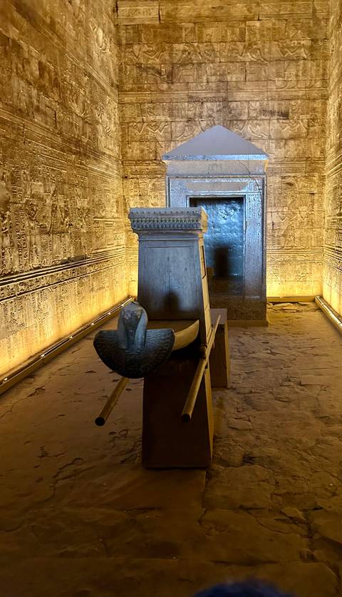 Ancient Egyptian carvings in a dimly lit temple corridor.
