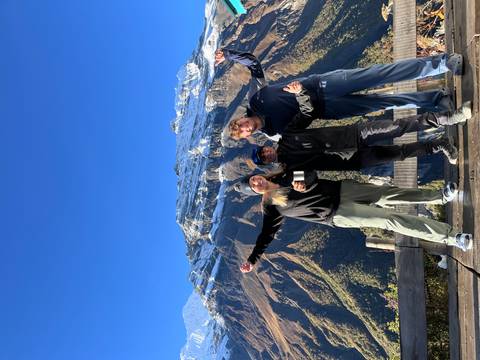 Three hikers with mountains in the background celebrating.