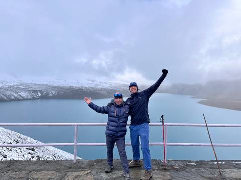 Two hikers celebrating on a viewpoint with a scenic lake and mountains.