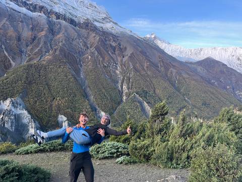 Two people posing playfully with dramatic mountains in the background.