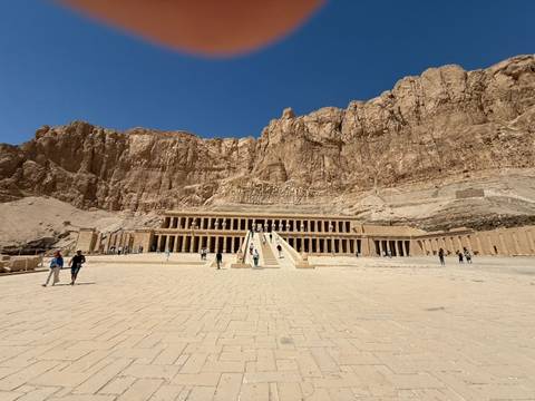 Visitors at Hatshepsut Temple with rocky backdrop.