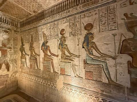 Ancient Egyptian wall depicting seated figures in relief.