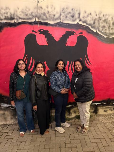 Four people standing in front of a mural.