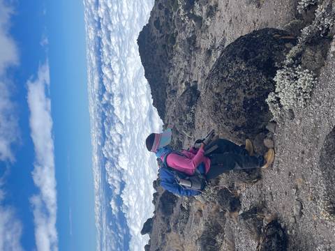 Person hiking with a backpack on a rocky mountain trail.