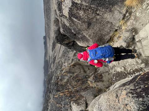 Person in red clothing hiking down a rocky trail.