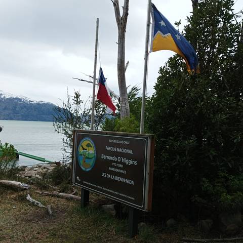 Entrance sign for Bernardo O'Higgins National Park with flags.