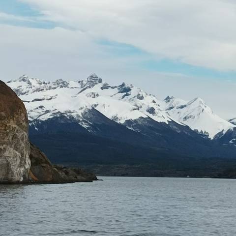 Snow-capped mountains rising above a lake and dark terrain.