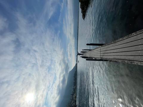 Person standing on a pier extending into a calm lake.