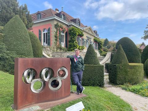 Person standing by an art installation with a house in the background.