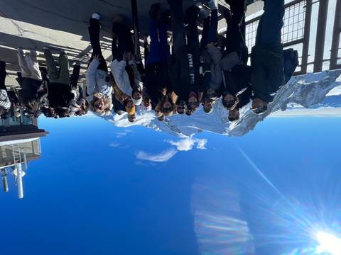 Group of people at a snowy mountain viewpoint on a sunny day.