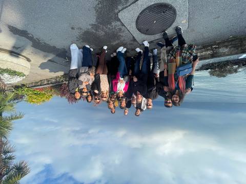 Group of people near a body of water with trees and plants around.