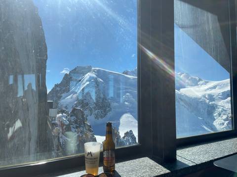 Snowy mountain peaks viewed through a window with reflections.