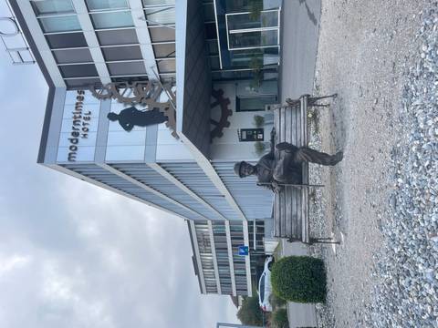 Modern hotel building with a sculpture of a man on a bench.