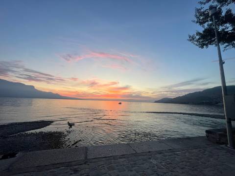 Sunset over a lake with ripples in the water and clouds.