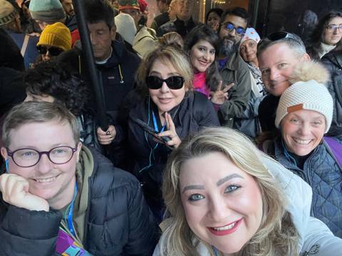 Group of people smiling indoors, some posing with peace signs.
