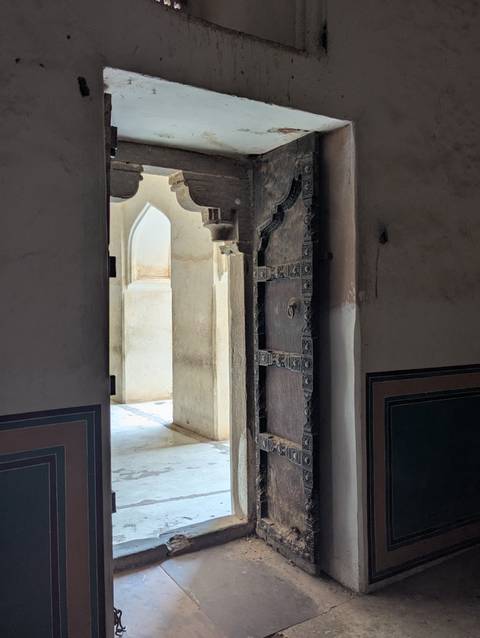 Dimly lit corridor with an intricately decorated door.