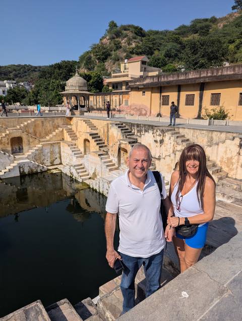 Two people posing near a stepped well.