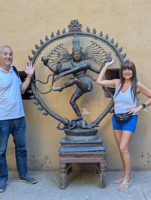 Two people posing beside a statue of Shiva.