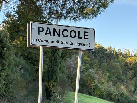 A road sign for Pancole with trees in the background.