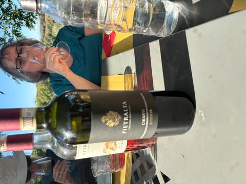 Wine tasting setup with a bottle of Chianti and a person drinking wine.