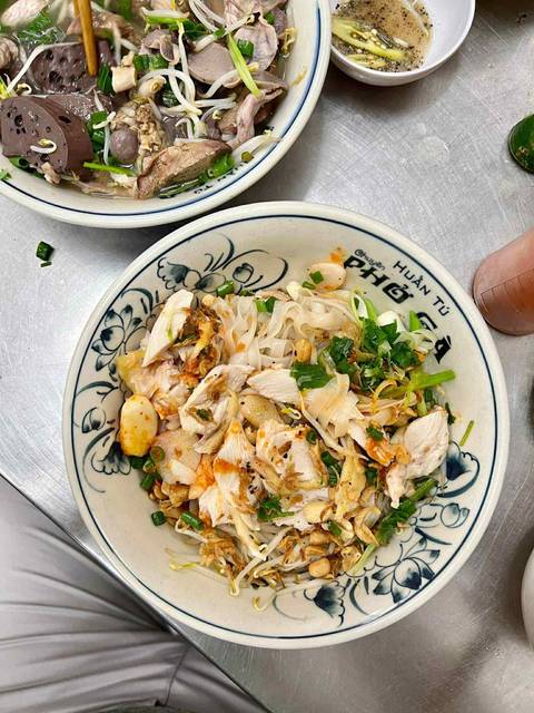 Bowl of Vietnamese noodle soup with chicken and vegetables.