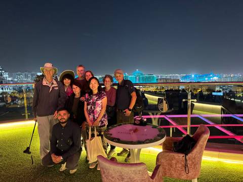 Group of people on a rooftop with city lights in the background at night.
