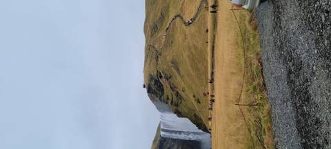 Large waterfall with people hiking up the path.