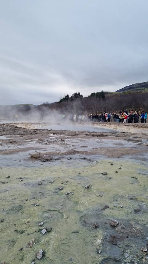 Hot springs with steam and a crowd of people.