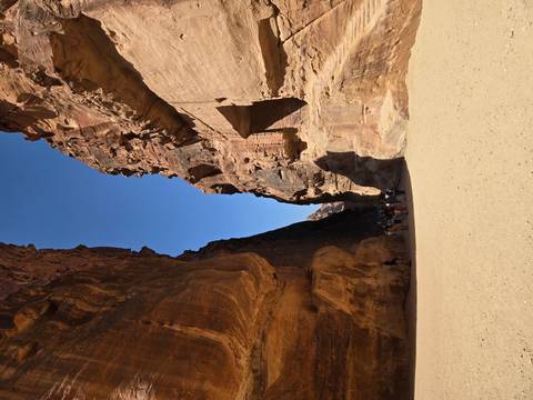 Group of people walking through a narrow canyon with tall rock walls.
