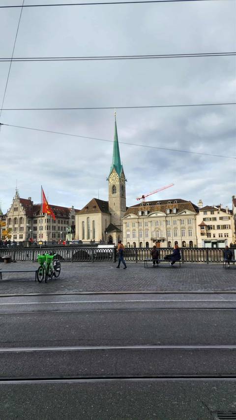 People walking in front of historic buildings with a flag on display.