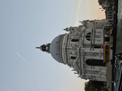 Historic dome-shaped building by the water at sunset.