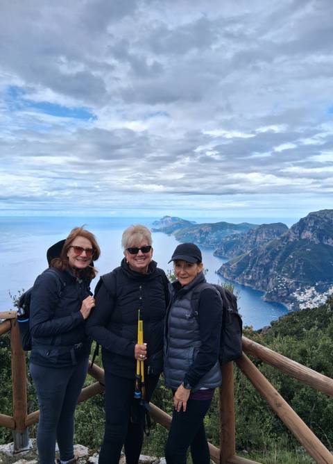 Three people posing with a scenic coastal view.