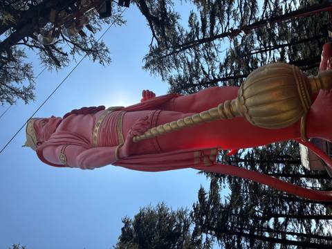 Large red statue against a blue sky and trees in the background.