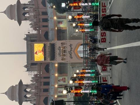 Border gate with people walking, displaying flags and lights.