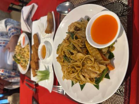 Plates of food including noodles and spring rolls on a dining table