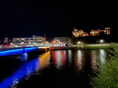 Night view of a lit-up city bridge reflecting in water.