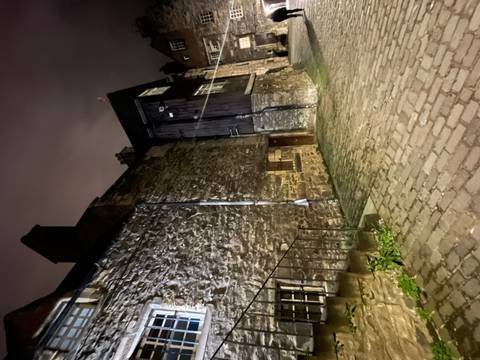 Old stone building at night with cobblestone path.