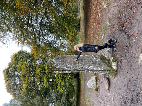 Person touching an ancient standing stone in a natural setting.