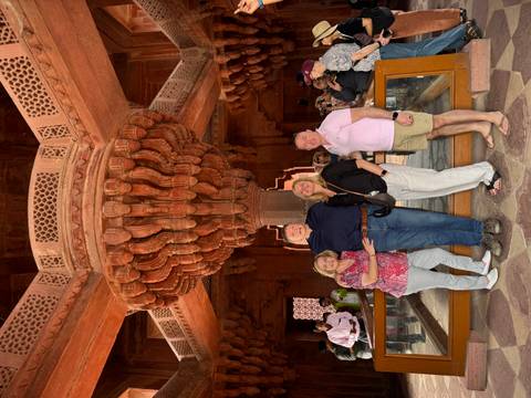 Group of people posing under an elaborately carved ceiling.