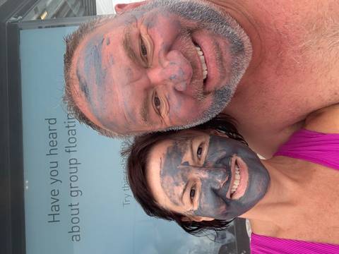 Two people with face masks on, smiling at the camera.