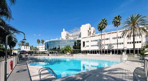 Luxurious hotel pool area with modern architecture and palm trees.