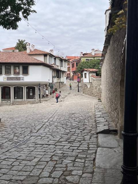 People walking on a cobblestone street in a historical town.