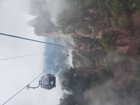 Cable cars moving over a mountainous, foggy landscape.