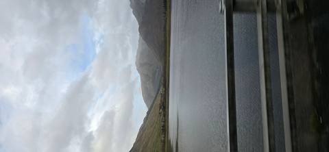 Mountainous landscape with water body viewed from a bridge.