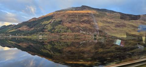 Reflection of a mountain in a still lake with lush surroundings.