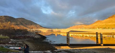 Bridge over a valley with tall mountains in the background.
